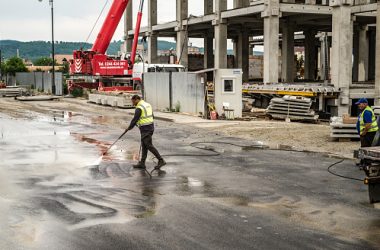 Sibiu, Romania - June 05, 2019, Worker washes the dirty pavement with water in front of the mall Festival Centrum building site from Sibiu city, Romania